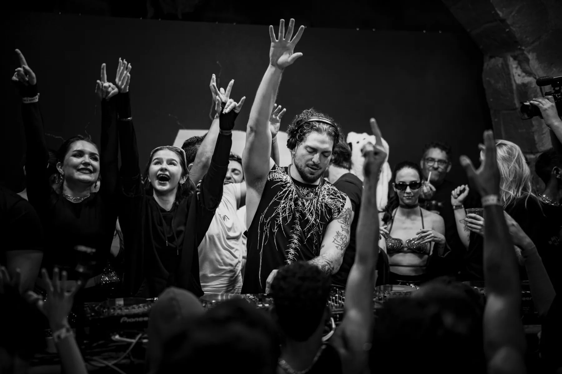 Crowd dancing around a DJ at a packed electronic music event